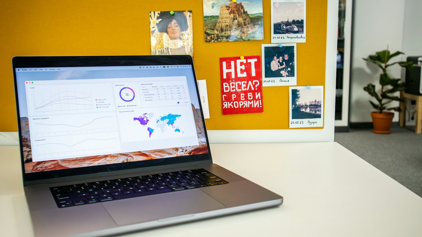 Laptop con dashboard di analisi dati su una scrivania bianca.